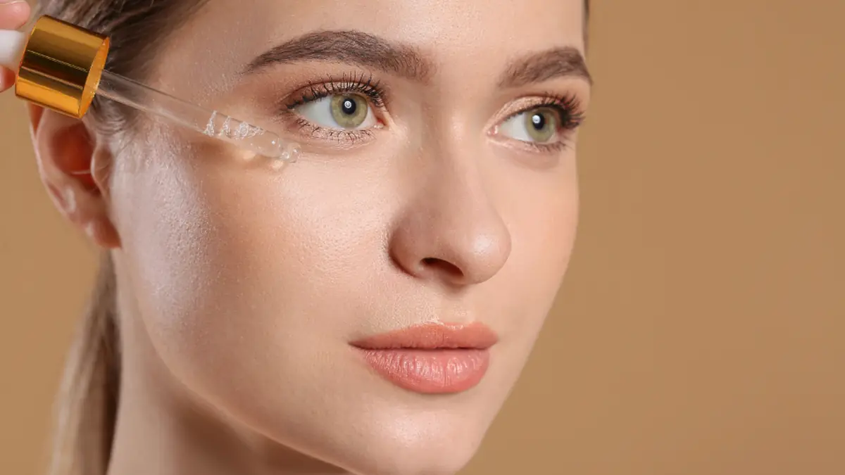 Woman applying facial serum with a glass dropper