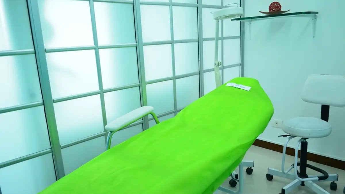 Clean treatment room with a padded treatment table and equipment