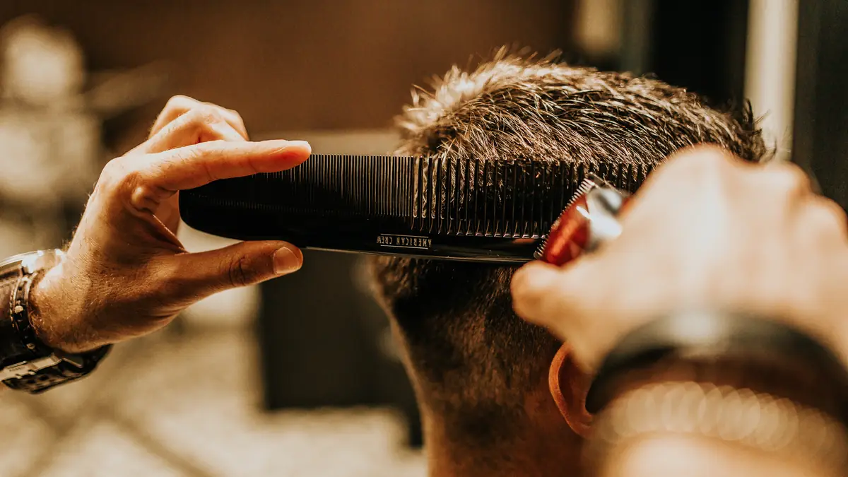 Barber cutting a client's hair with clippers and a comb