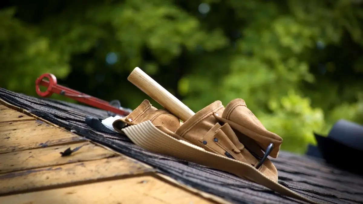 Carpentry tools and rolled roofing materials on a wooden roof deck