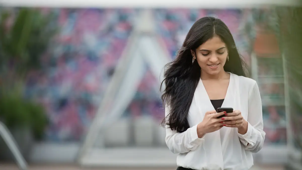 Woman reading a text message on her smartphone outdoors