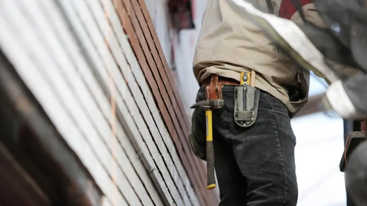 Tradesman wearing a tool belt walking up exterior stairs to a job